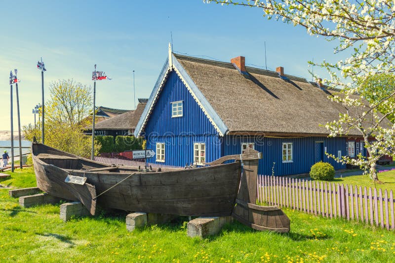 Beautiful old Lithuanian traditional wooden house with thatched roof and boat