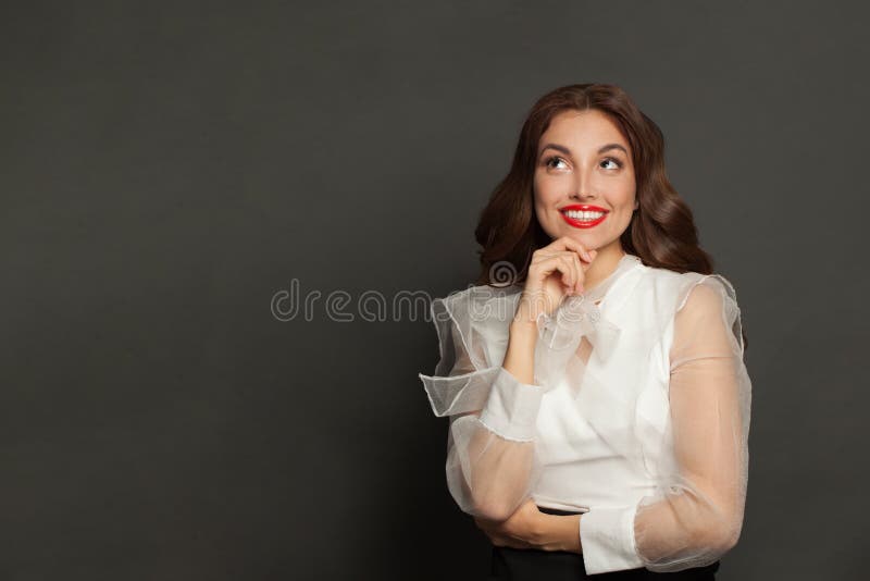 Beautiful optimistic woman fashion model with cute toothy smile looking up and standing on gray banner background