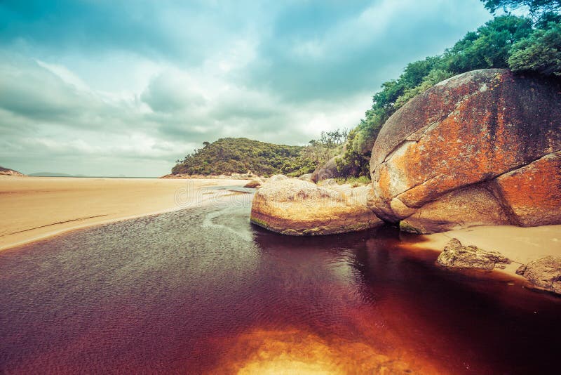 Beautiful orange rocks and brown water of Tidal River. Wilsons P