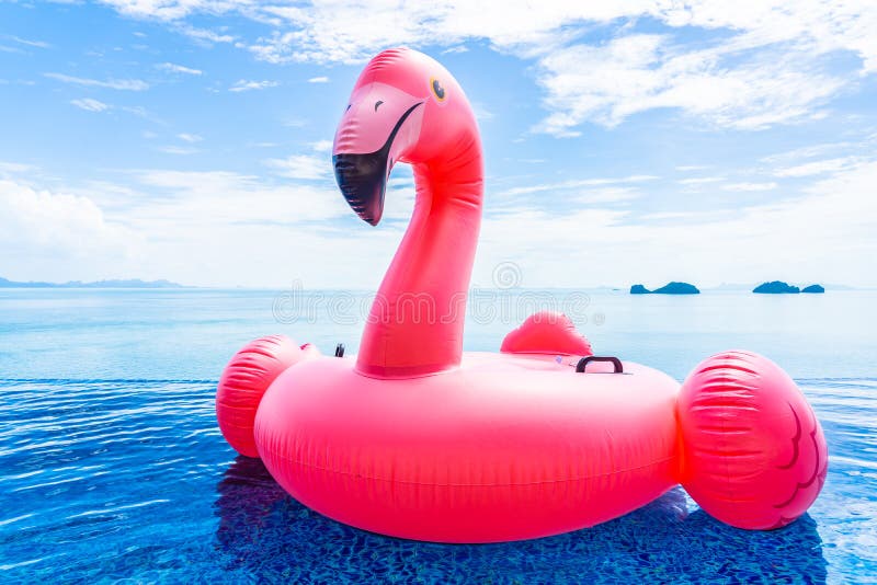 Beautiful outdoor swimming pool in hotel resort with flamingo float around sea ocean white cloud on blue sky