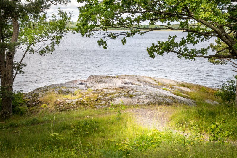 Beautiful peaceful and tranquil summer view of a path to a glade by the water with tree, grass and rock. stock photography Beautiful peaceful and tranquil summer view of a path to a glade by the water with tree, grass and rock. stock photography