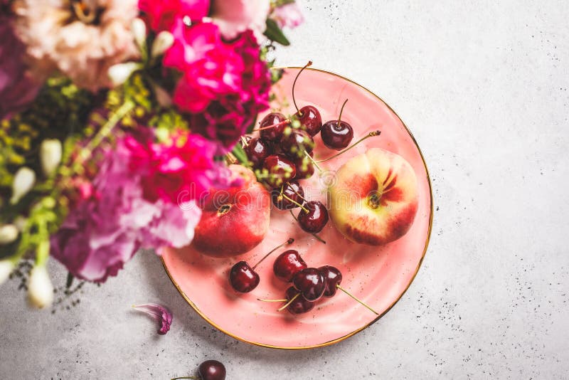 Beautiful pink food background. Flowers and berries on pink plate