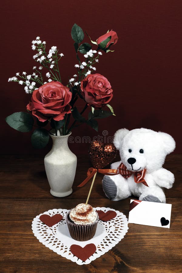 Beautiful pink roses in a vase accented with Baby`s Breath flowers, heart shaped white dollie with a decorated cup cake with a he