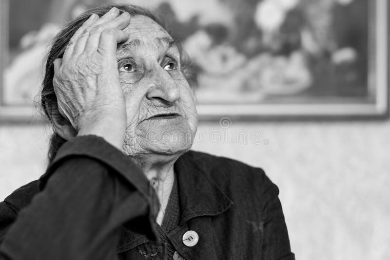 Krásná 80 let stará starší žena portrét. Černobílý obrázek starší ustarané ženy sedící na židli.