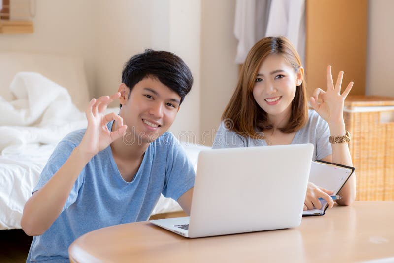 Beautiful portrait young asian couple working laptop with smile and happy sitting in bedroom