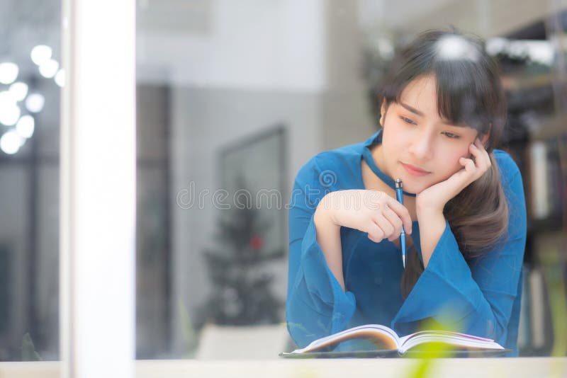 Beautiful portrait young asian woman writer smiling thinking idea and writing on notebook or diary with happy