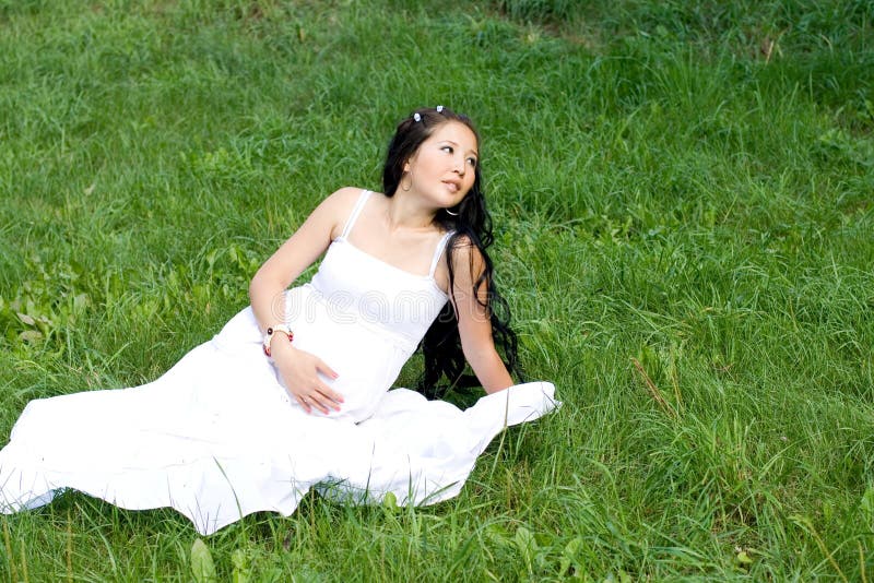 Beautiful pregnant girl sitting on grass