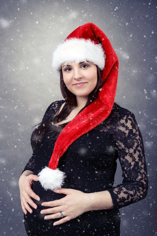 Beautiful pregnant santa woman tenderly holding her tummy