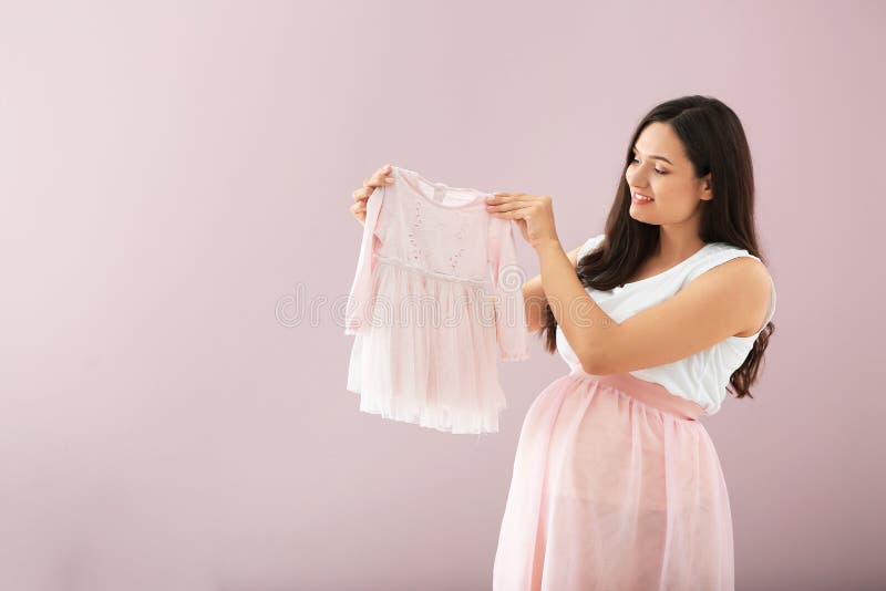 Beautiful pregnant woman with baby dress on color background royalty free stock photo Beautiful pregnant woman with baby dress on color background royalty free stock photo