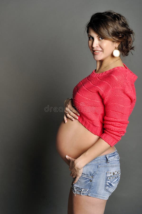 Beautiful pregnant woman on gray background in studio stock image