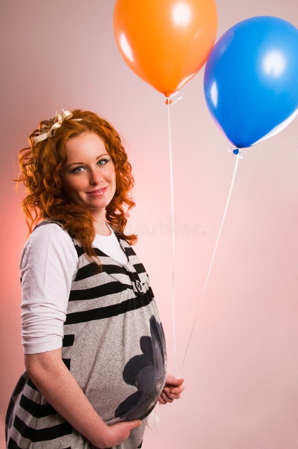 Beautiful pregnant woman holding balloons