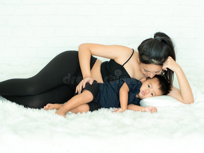 A beautiful pregnant woman lying in bed and caring for her son happily royalty free stock images A beautiful pregnant woman lying in bed and caring for her son happily royalty free stock images