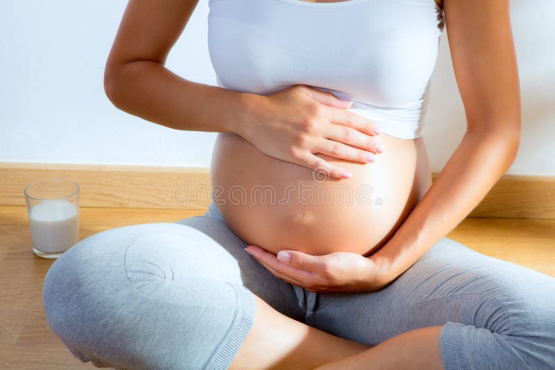 Hermoso una mujer masaje manos sobre el barriga sobre el sobre el piso.