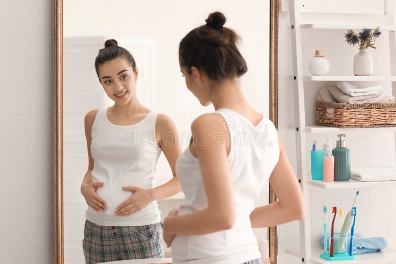 Beautiful pregnant woman near mirror in morning