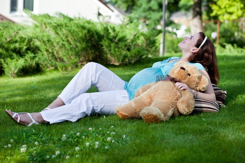 Beautiful pregnant woman relaxing on green grass