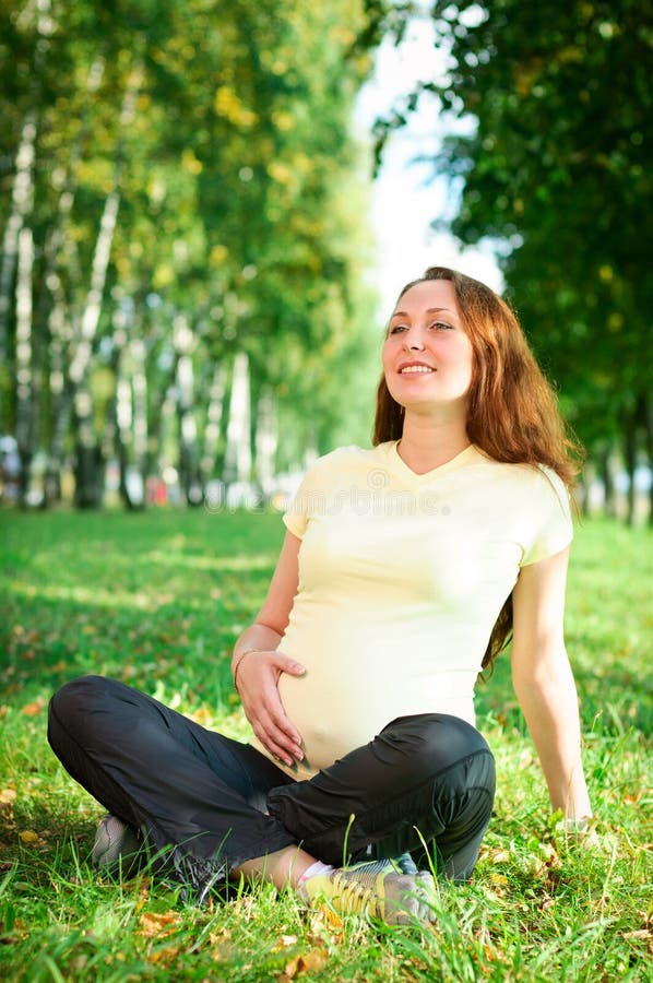 Beautiful pregnant woman relaxing in the park