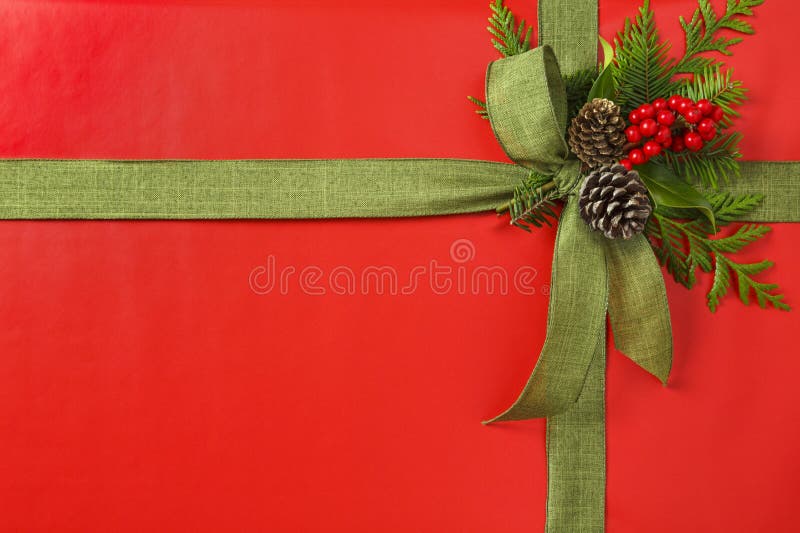 Beautiful red and green Christmas gift present with fabric ribbon bow and botanical decorations. Horizontal background border.