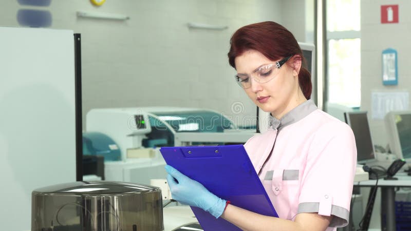 Young female scientist taking notes at the modern lab stock video Young female scientist taking notes at the modern lab stock video