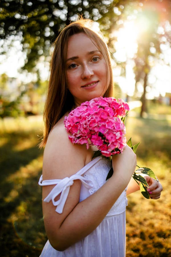 Beautiful Woman With Flowers In Spring Sunshine Girl Is Holding Flowers On Meadow In Park At