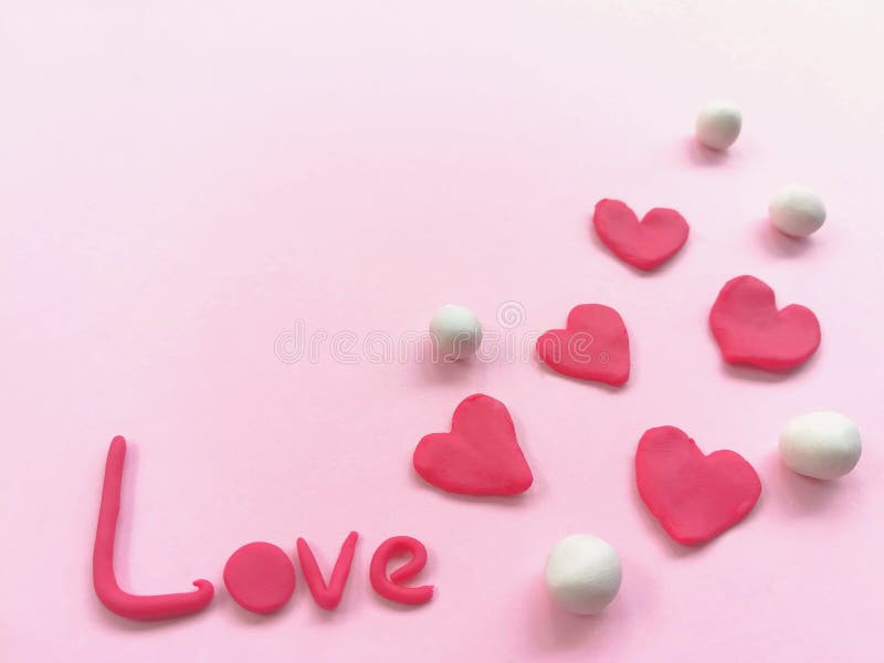 Beautiful red heart and love word plasticine, colorful clay dough, pink background