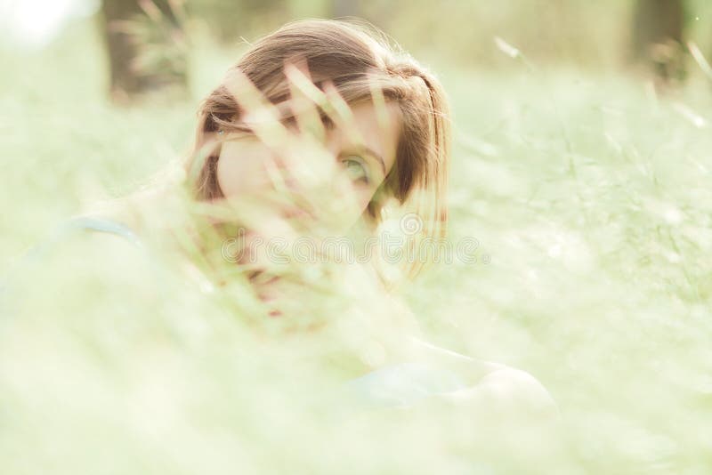 Beautiful romantic girl sitting on field of spikelets and enjoying nature, young elegant woman face hiding behind grass royalty free stock image Beautiful romantic girl sitting on field of spikelets and enjoying nature, young elegant woman face hiding behind grass royalty free stock image