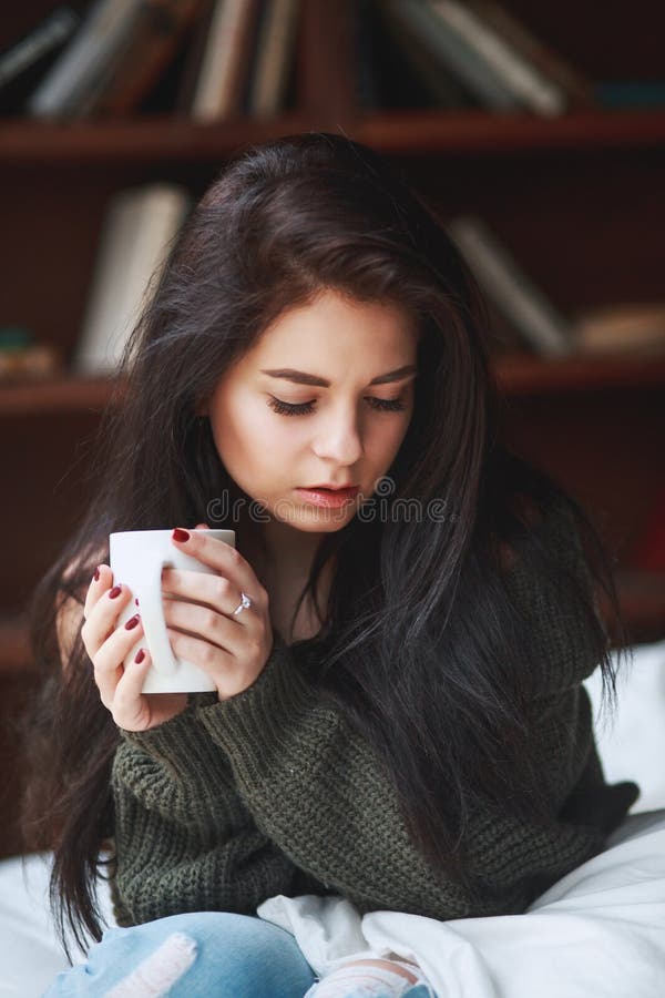 Beautiful sad brunette woman with a cup of coffee or tea