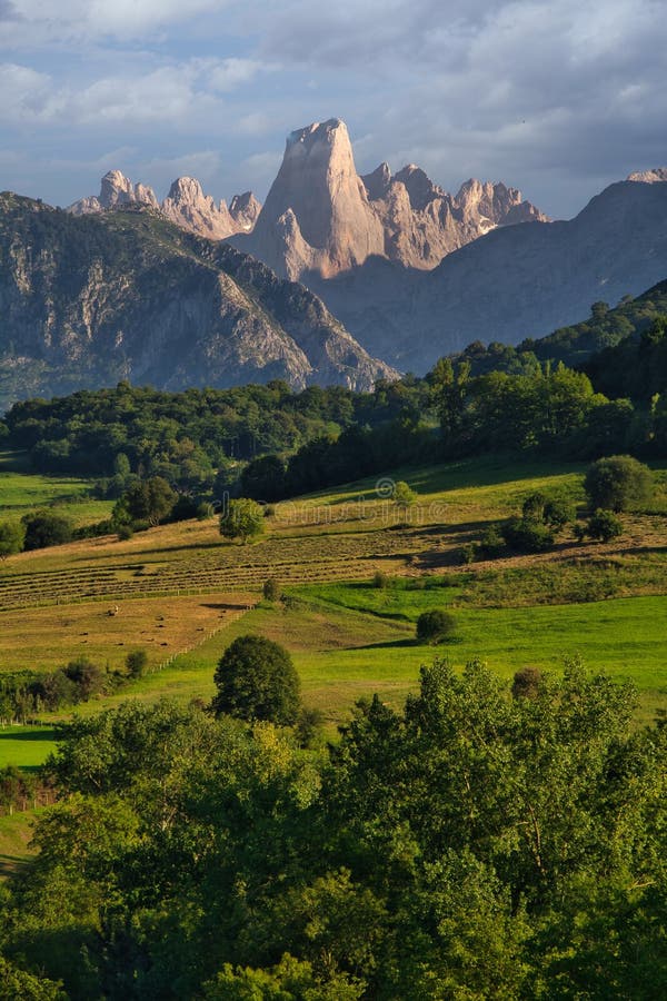 Beautiful Scene of mountains, green pastures under a cloudy blue sky in Naranjo de Bulnes, Spain. A beautiful Scene of mountains, green pastures under a cloudy