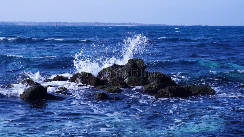 It is a beautiful scenery where a wave crashes against a blue sea rock of Udo, Jeju Island. stock photo It is a beautiful scenery where a wave crashes against a blue sea rock of Udo, Jeju Island. stock photo