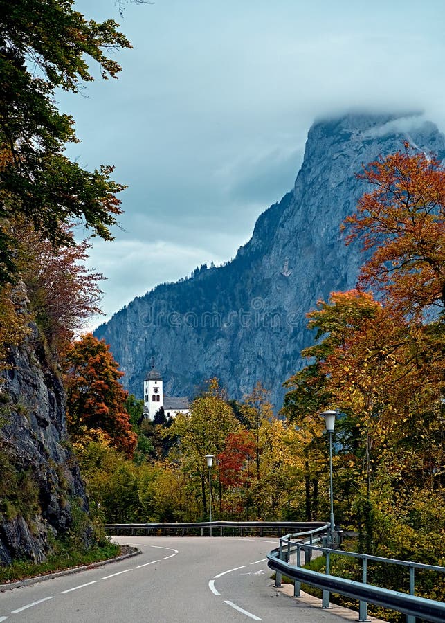 Beautiful scenic sunset over Austrian alps lake. Highway road infront of church on the rock with clouds over Traunstein mountain stock image Beautiful scenic sunset over Austrian alps lake. Highway road infront of church on the rock with clouds over Traunstein mountain stock image