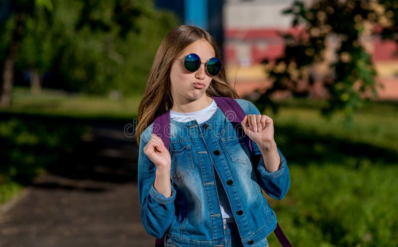 Beautiful blonde teen girl 13-14 year old wearing stylish clothes posing in  autumn park. Looking at camera Stock Photo - Alamy