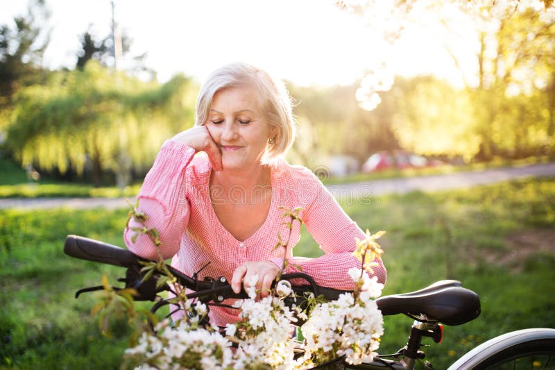 Beautiful senior woman with bicycle outside in spring nature. stock photography Beautiful senior woman with bicycle outside in spring nature. stock photography