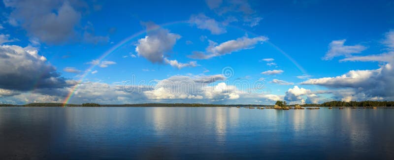 Beautiful september rainbow over the lake in panorama landscape