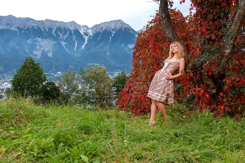 Beautiful sexy blond young woman in dirndl fashion is standing in front of autumn leaves in the Innsbruck Mountains