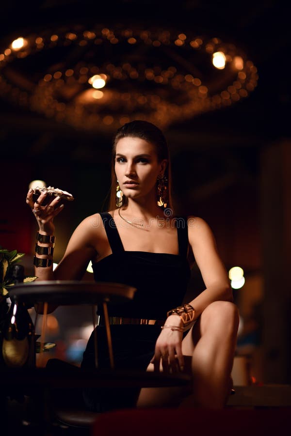Beautiful fashion brunette woman in expensive interior restaurant eat oysters royalty free stock image Beautiful fashion brunette woman in expensive interior restaurant eat oysters royalty free stock image