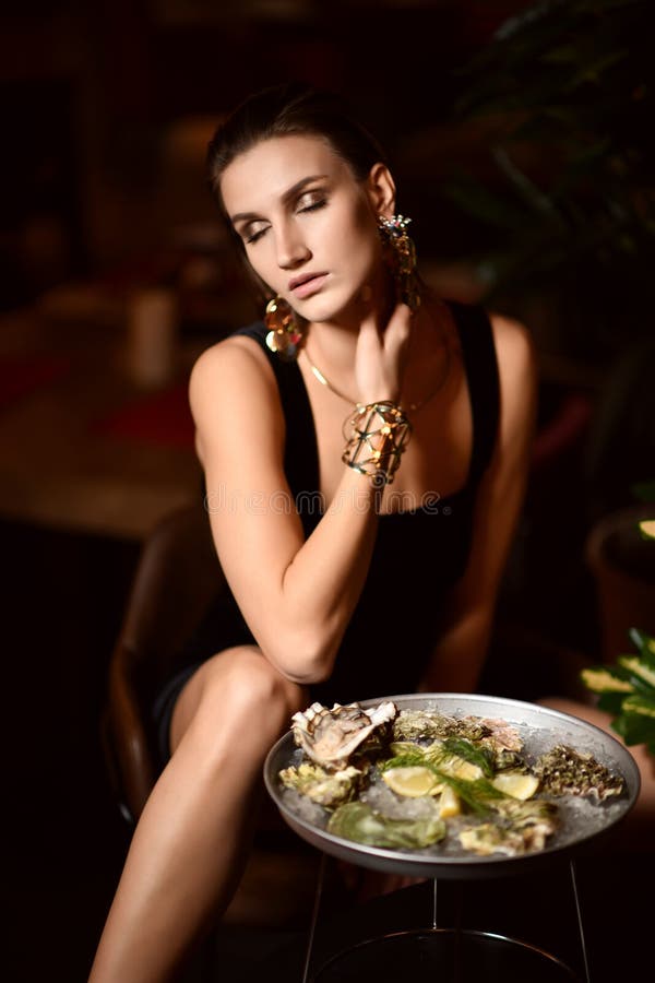 Beautiful fashion brunette woman in expensive interior restaurant eat oysters stock images Beautiful fashion brunette woman in expensive interior restaurant eat oysters stock images