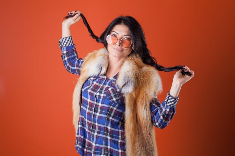 Pretty woman model pose wear plaid shirt and fur vest on the orange studio background royalty free stock photography Pretty woman model pose wear plaid shirt and fur vest on the orange studio background royalty free stock photography