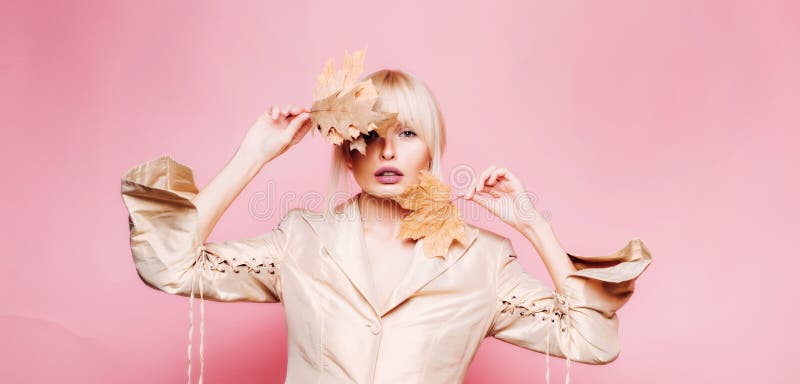 Beautiful sexy woman holding gold leaf on yellow background. Surprise woman playing with leaves and looking at camera royalty free stock image Beautiful sexy woman holding gold leaf on yellow background. Surprise woman playing with leaves and looking at camera royalty free stock image