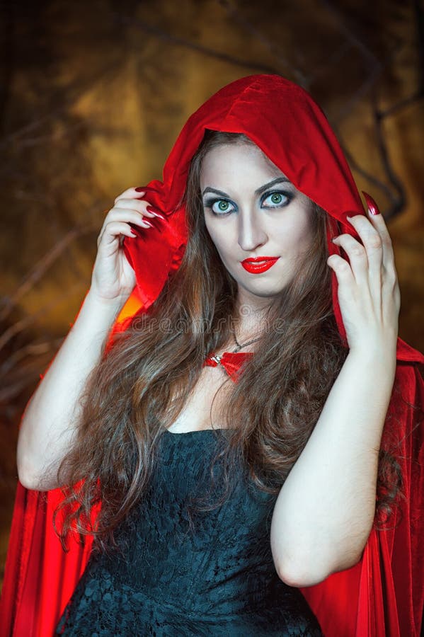 Beautiful sexy woman witch with long hair wearing red cloak