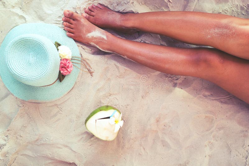 Beautiful of women tan. relax on sandy beach with hat and coconut cocktail.