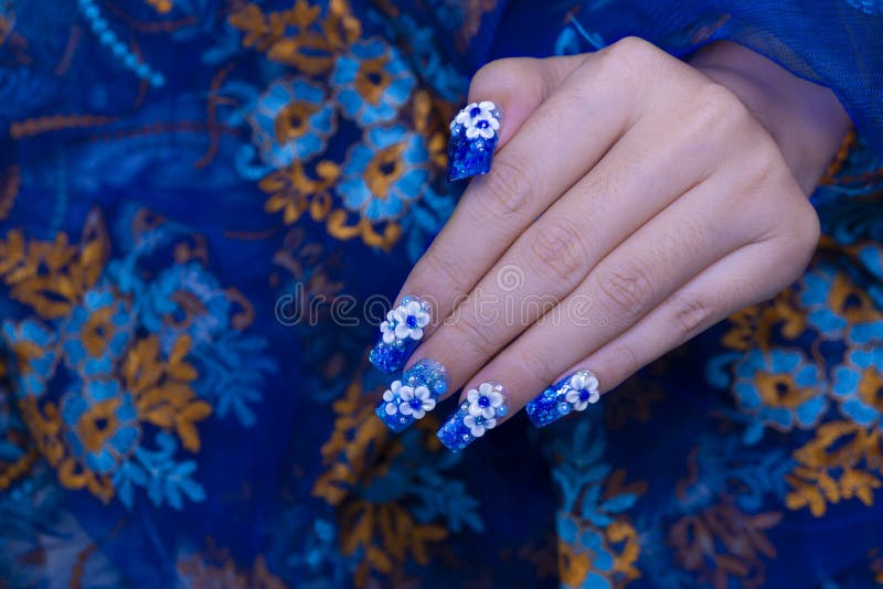 Beautiful shiny dark blue glitter gel nail art ombre design painting 3D white cute flower decorated with rhinestone on woman square shape fingernail. Beautiful shiny dark blue glitter gel nail art ombre design painting 3D white cute flower decorated with rhinestone on woman square shape fingernail