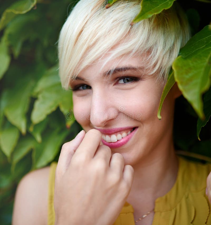 Beautiful Short Haired Platinum Blond Woman Standing Against An Ivy