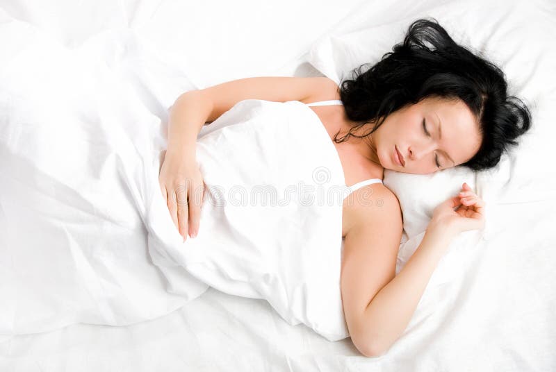 Beautiful young brunette woman sleeping peacefully on the white sheets. Beautiful young brunette woman sleeping peacefully on the white sheets