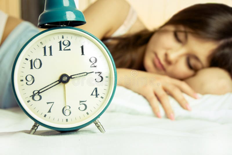 Beautiful sleeping woman with an alarm clock