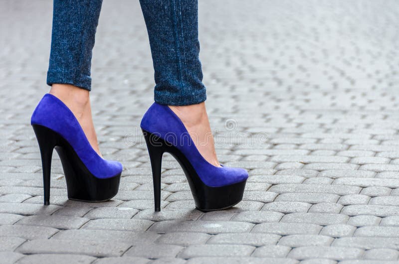 Beautiful slender female legs in tight jeans and blue shoes on a stock images Beautiful slender female legs in tight jeans and blue shoes on a stock images