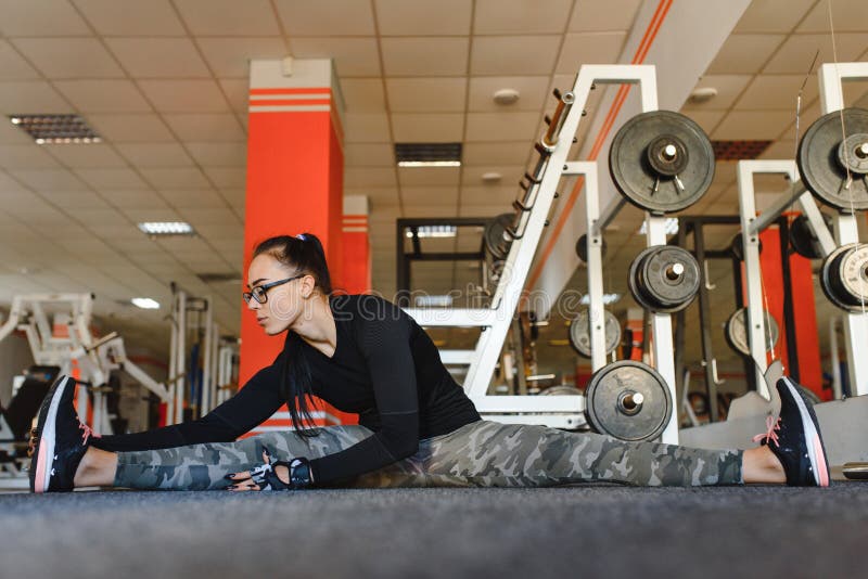 Beautiful Slim Brunette Doing Some Stretching Exercises In A Gym Stock