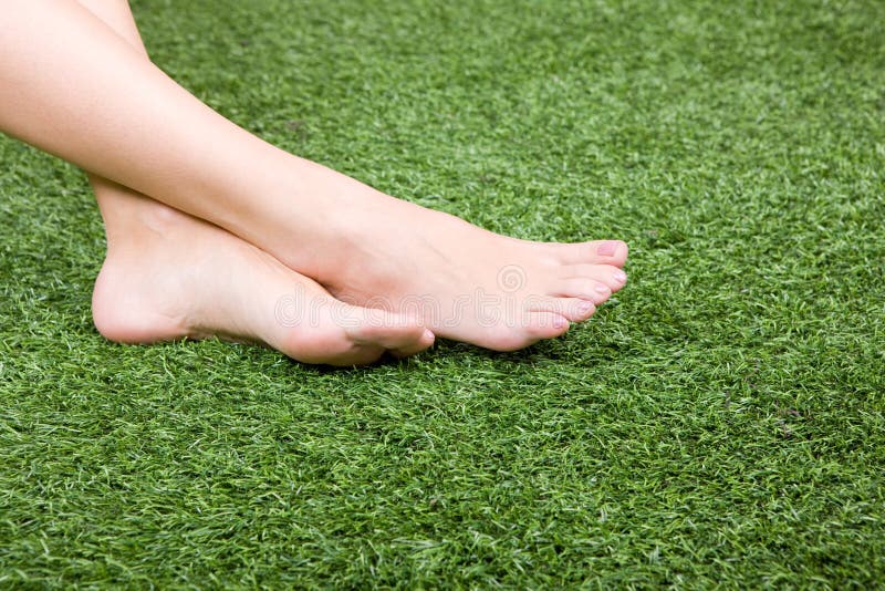 Beautiful slim female feet on green grass