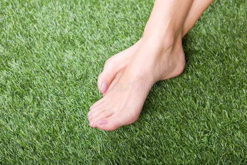 Beautiful slim female feet on green grass