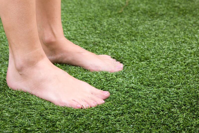 Beautiful slim female feet on green grass