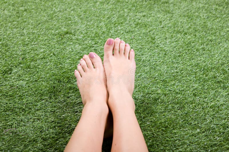 Beautiful slim female feet on green grass