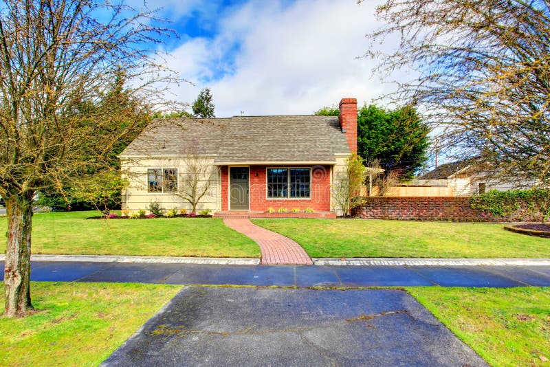 One story siding house with tile roof and brick trim. View of the front exterior , walk way and green lawn. One story siding house with tile roof and brick trim. View of the front exterior , walk way and green lawn